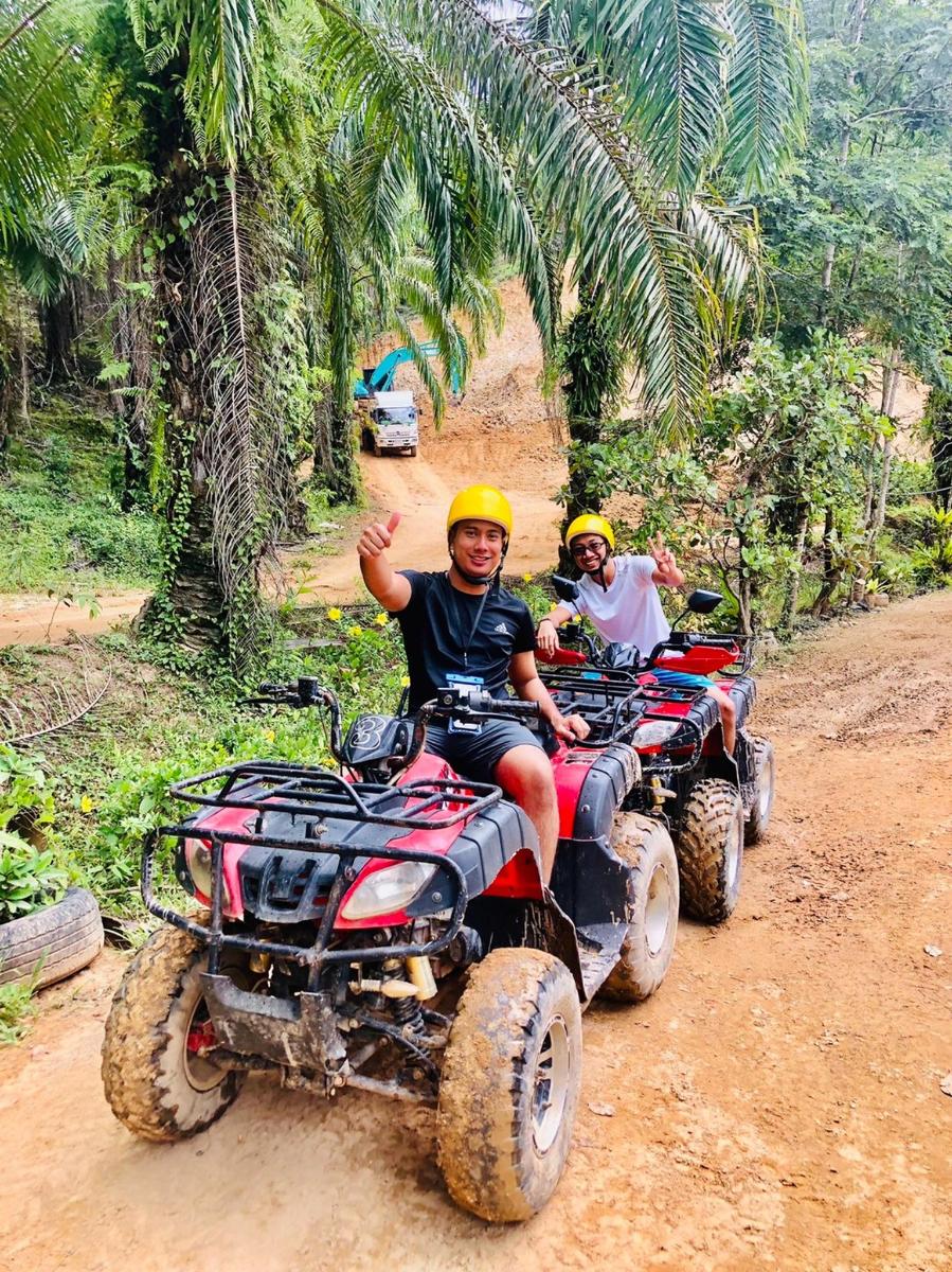 dues persones que condueixen quads per un camí de terra