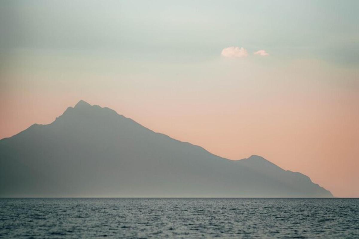Una vista de una montaña desde el océano al atardecer.