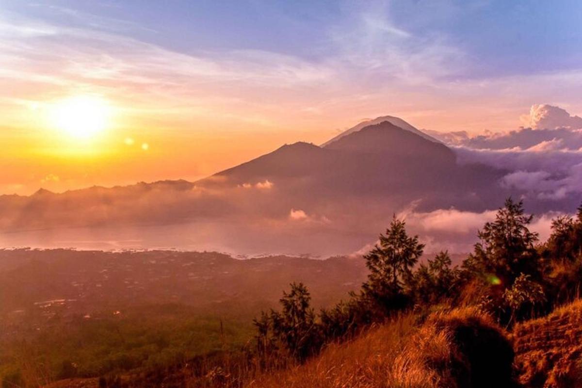 a view of a mountain with the sun in the background