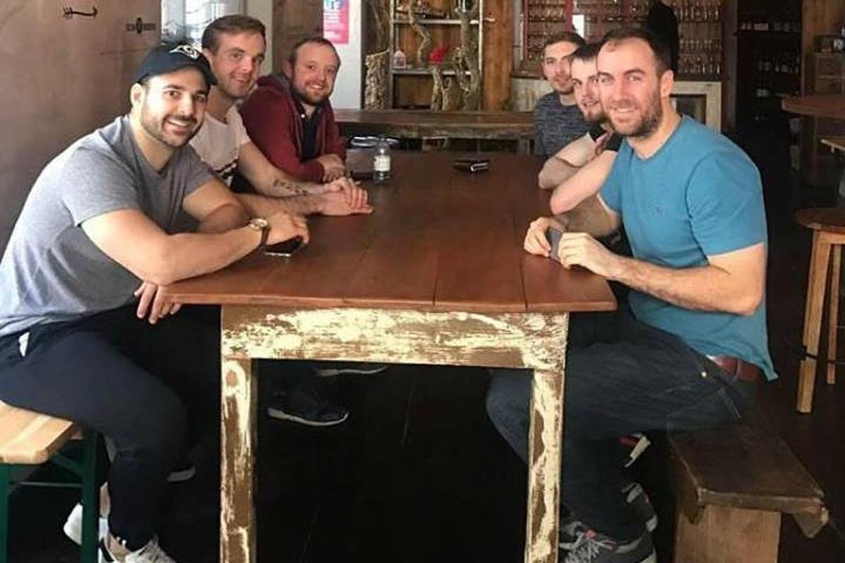 grupp mehi istub puust laua ümber
