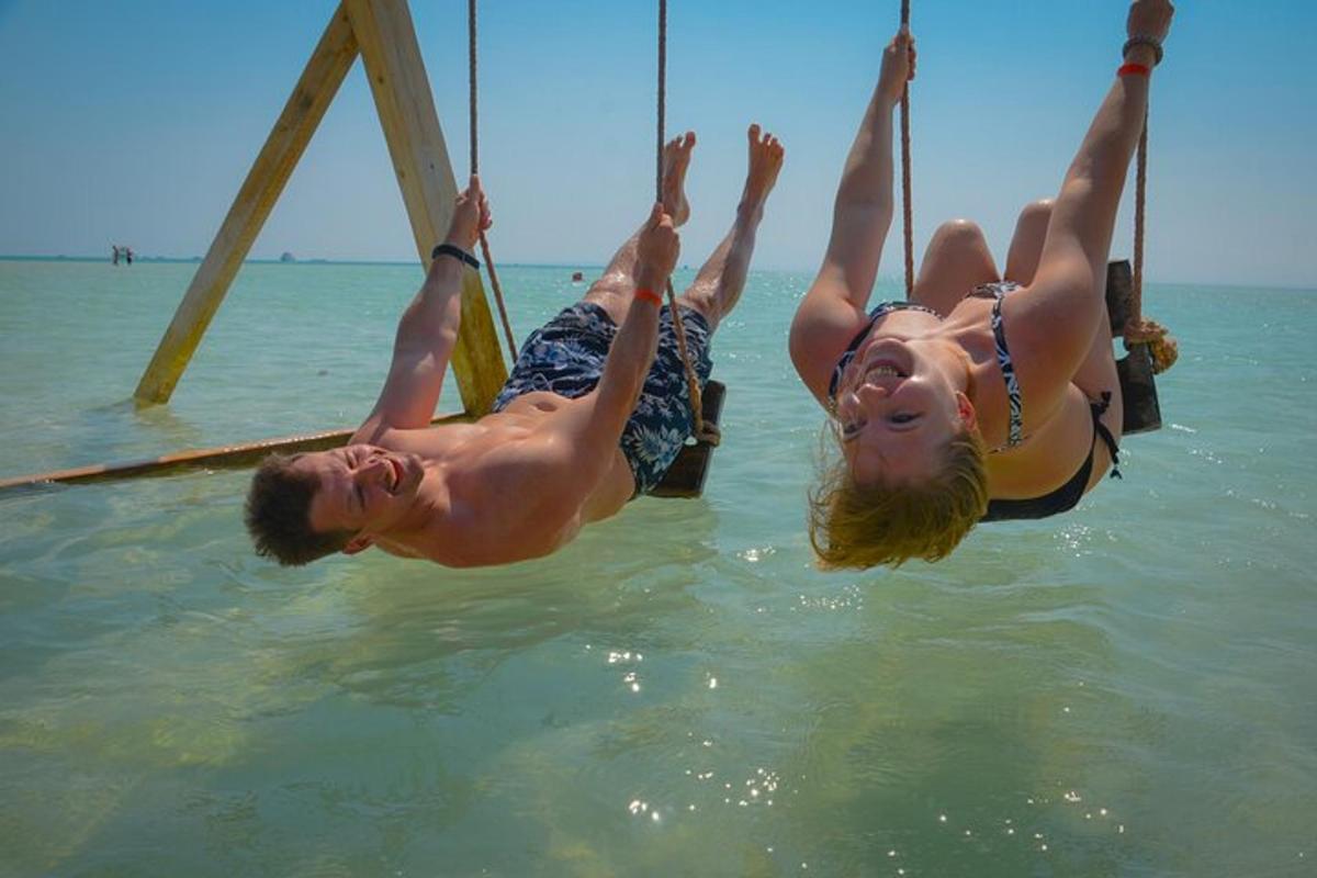Dos personas en el agua en un columpio de cuerda en el agua