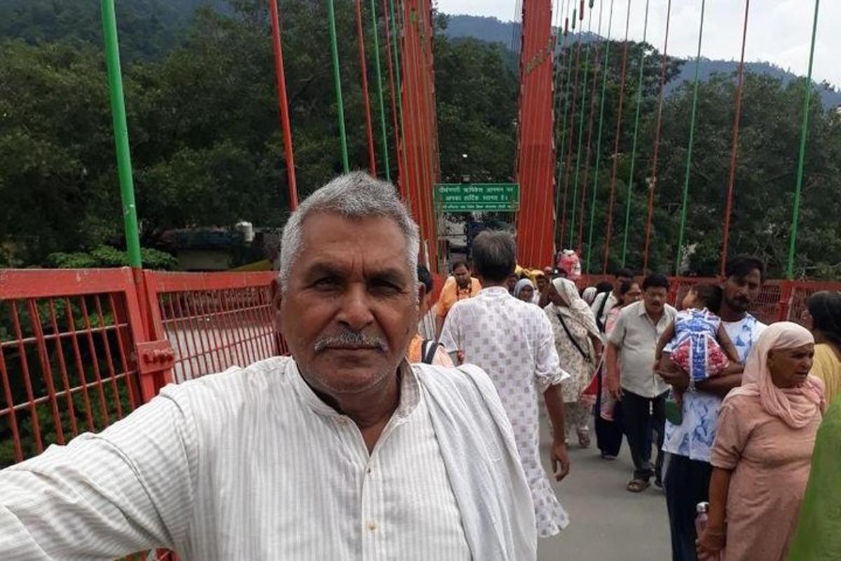 Un hombre mayor de pie en un puente colgante