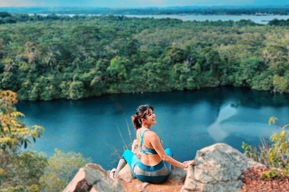 una dona asseguda en una roca amb vistes a un llac