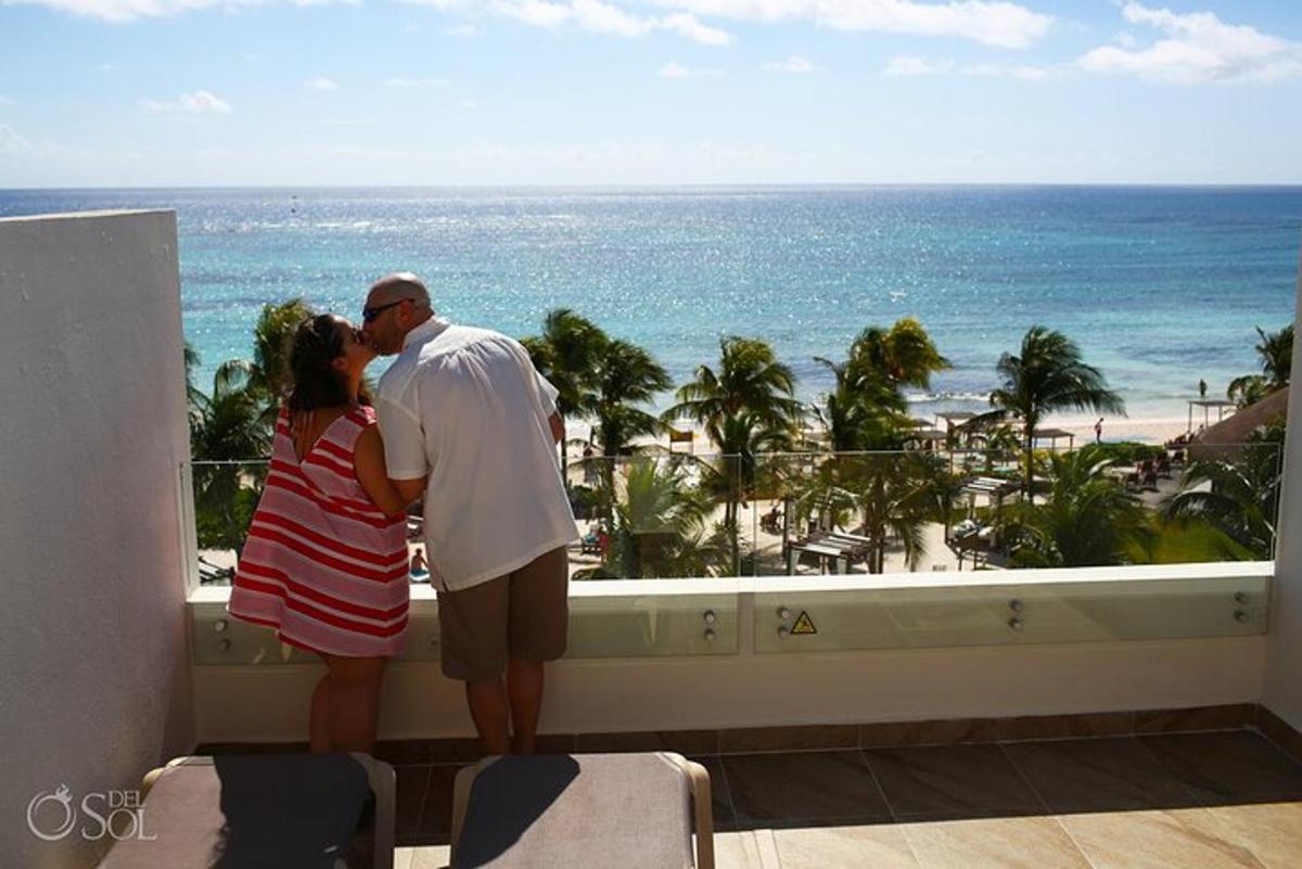un uomo e una donna in piedi su un balcone che guardano l'oceano