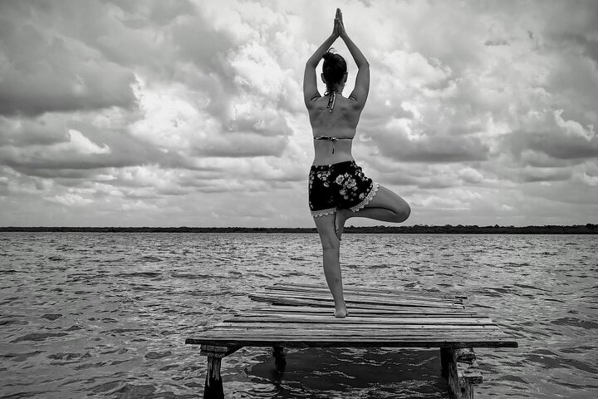 a woman doing a pose on a dock in the water