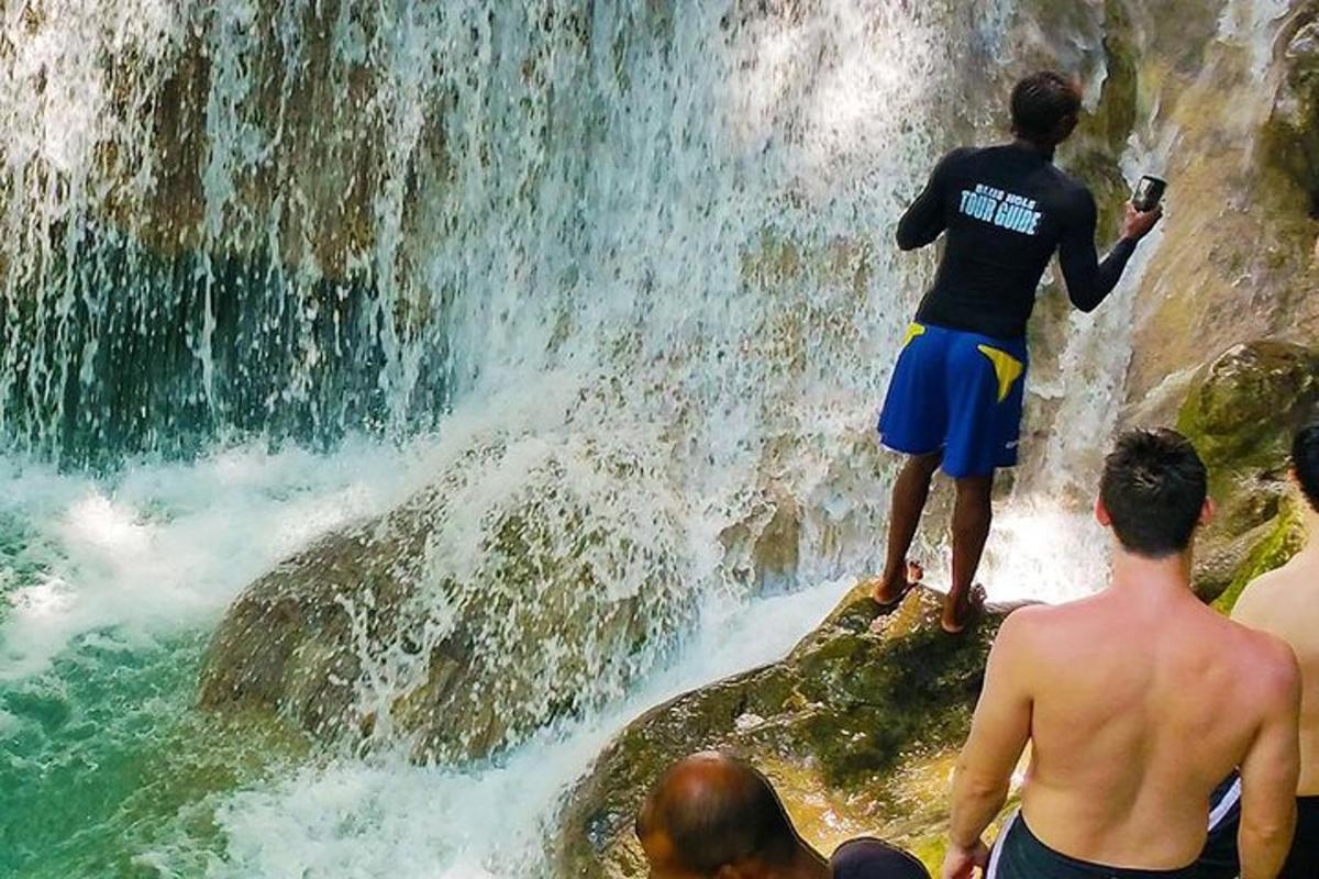 un home dret sobre una roca davant d'una cascada