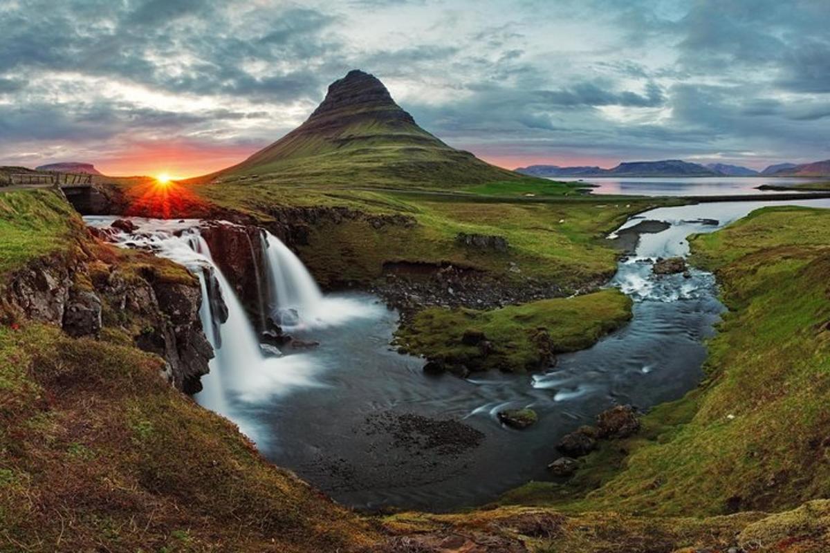 un tramonto su una cascata con una montagna sullo sfondo