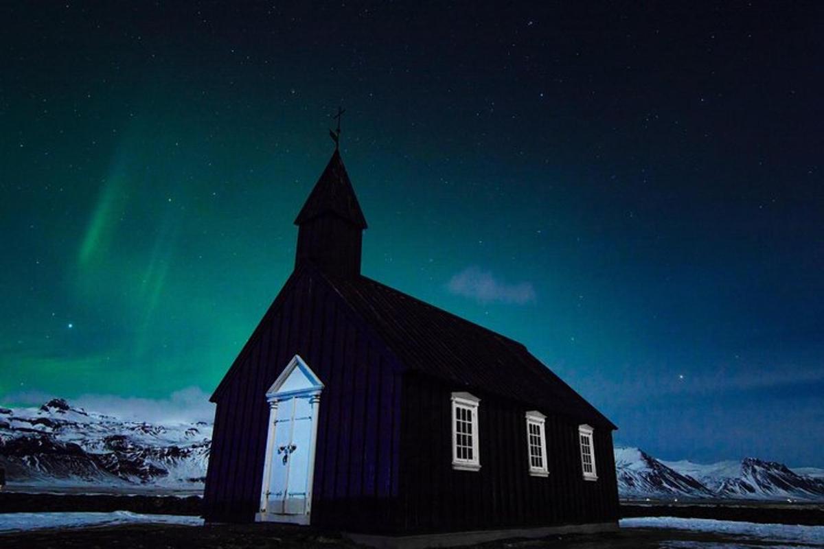 una chiesa nera con l'aurora boreale nel cielo