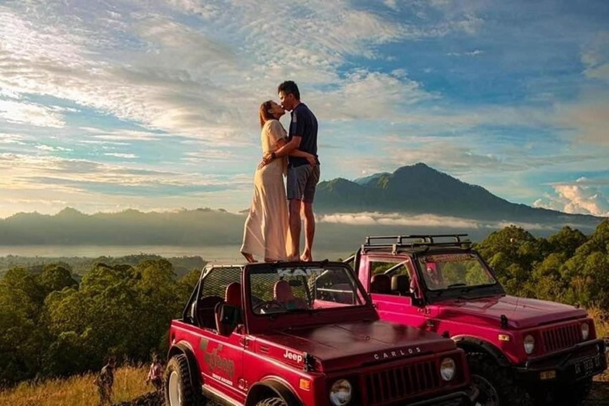 Una pareja parada encima de un jeep rojo