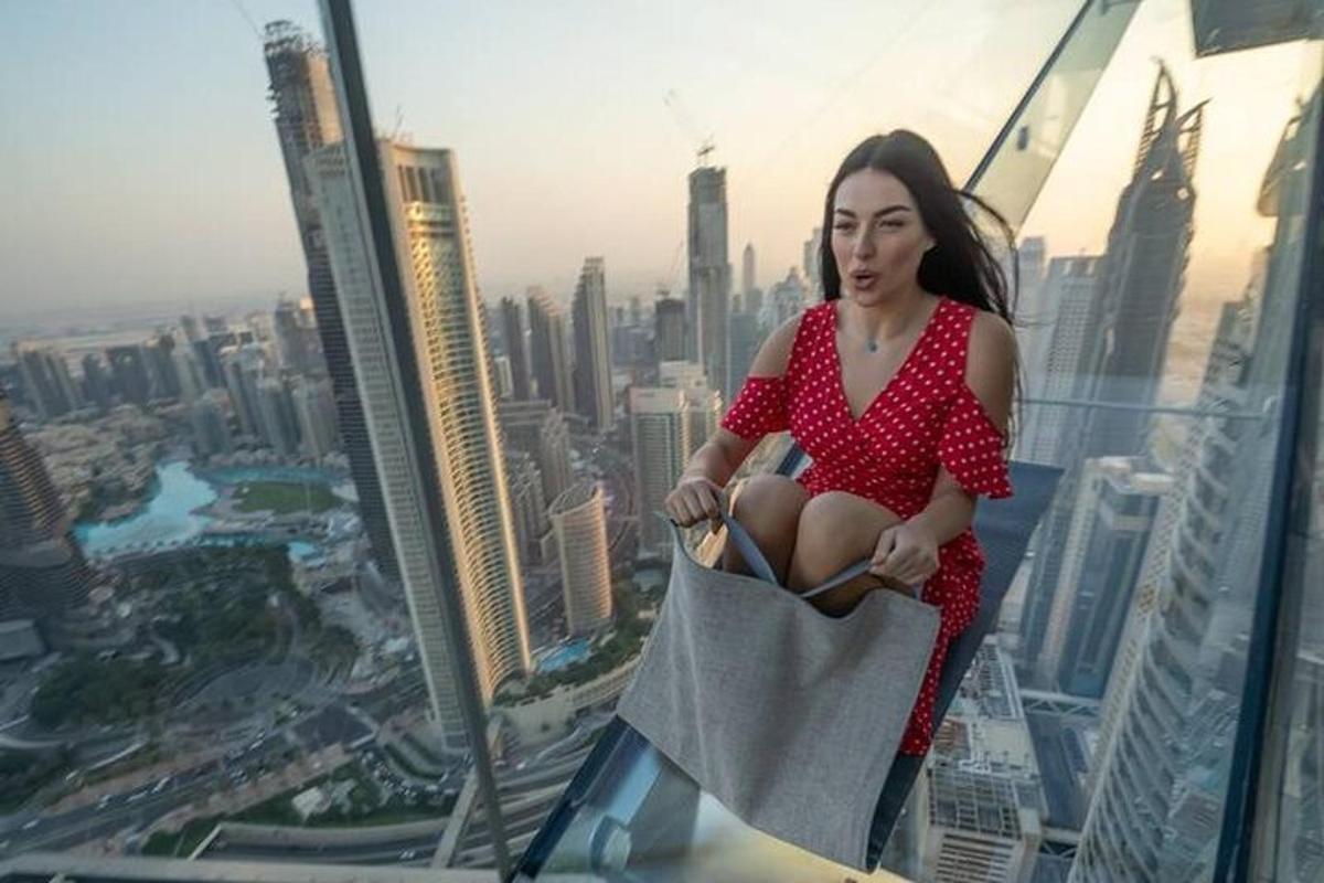 a woman in a red dress sitting on top of a skyscraper