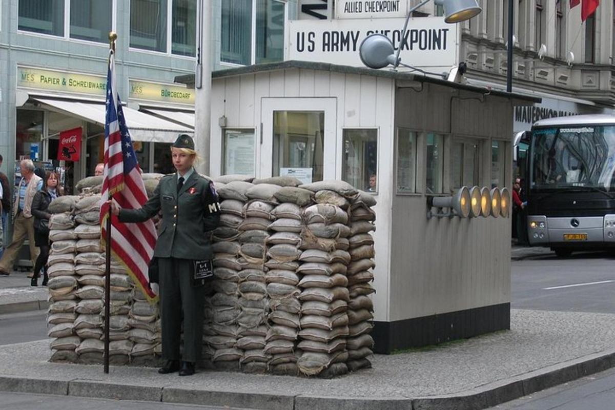 Bir binanın yanında Amerikan bayrağı tutan üniformalı bir adam