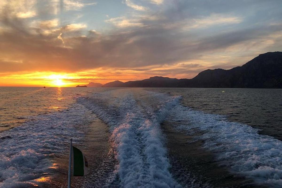 een boot die bij zonsondergang een kielzog in de oceaan achterlaat