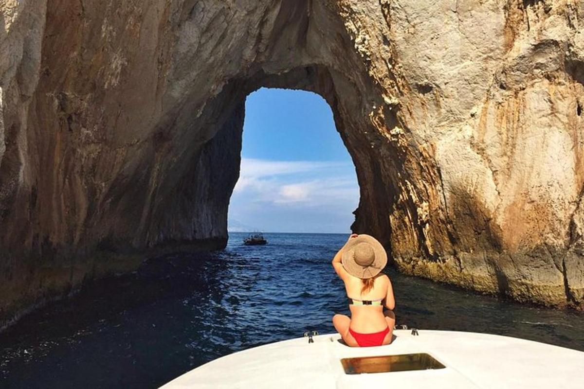 μια γυναίκα με καπέλο που κάθεται σε μια βάρκα μπροστά σε μια σπηλιά