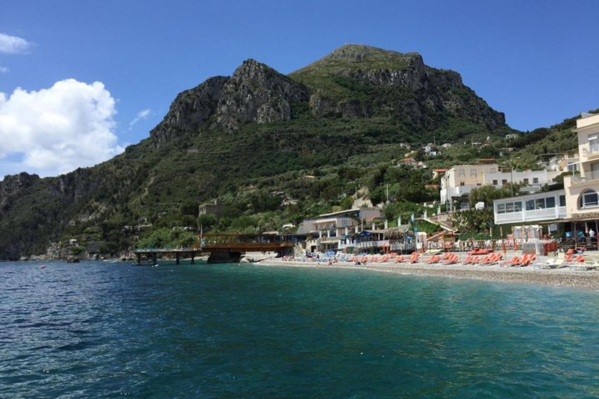 ein Strand mit Stühlen und Sonnenschirmen und ein Berg