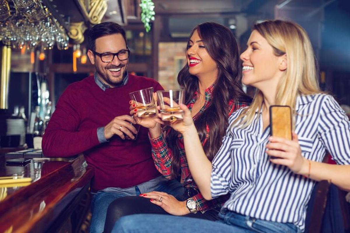 três pessoas sentadas em um bar bebendo vinho