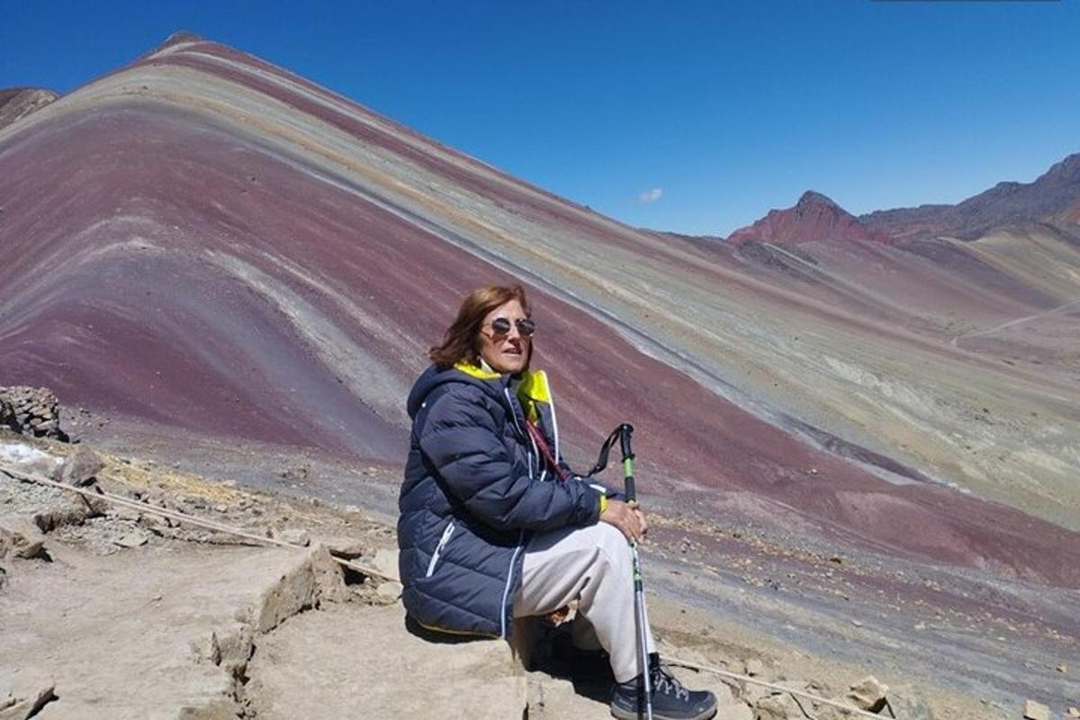una persona seduta su una roccia di fronte a una montagna