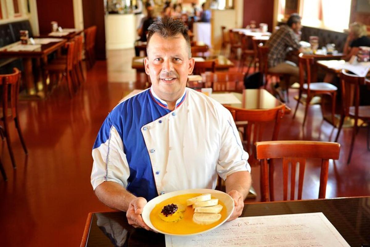 en mann som holder en tallerken med mat på en restaurant