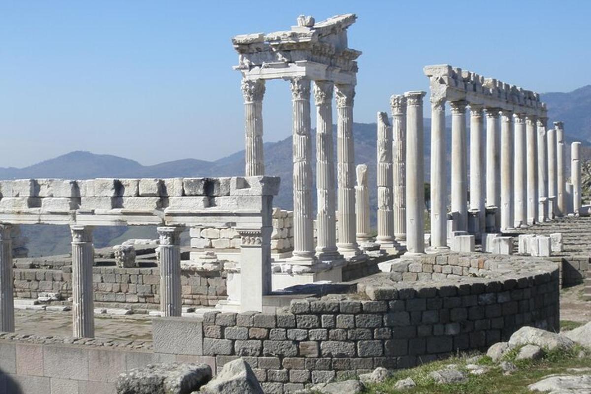 a group of columns in a building with mountains in the background