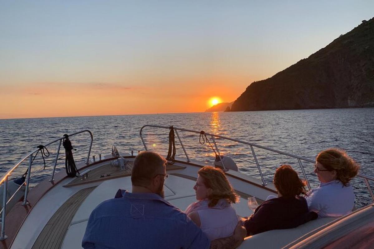 a group of people sitting on a boat watching the sunset