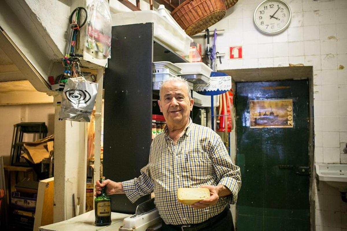 un bărbat care stă în bucătărie și ține în mână o bucată de brânză