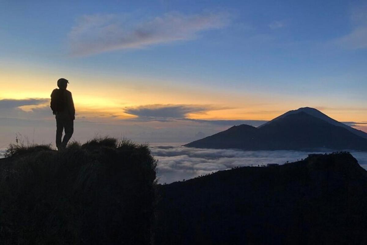 seorang lelaki berdiri di atas bukit melihat matahari terbenam