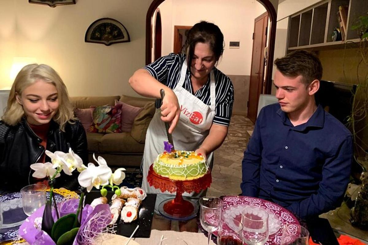 a group of people standing around a table cutting a cake