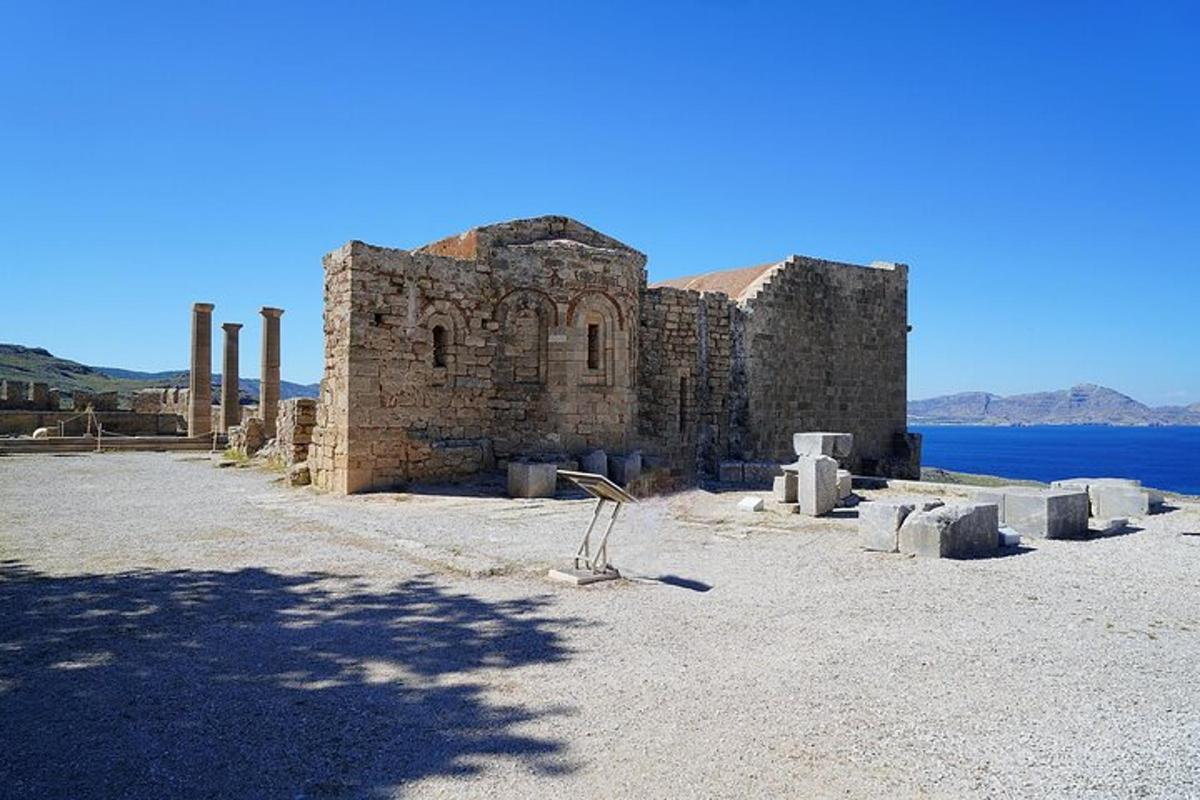 an old stone building with columns and a body of water