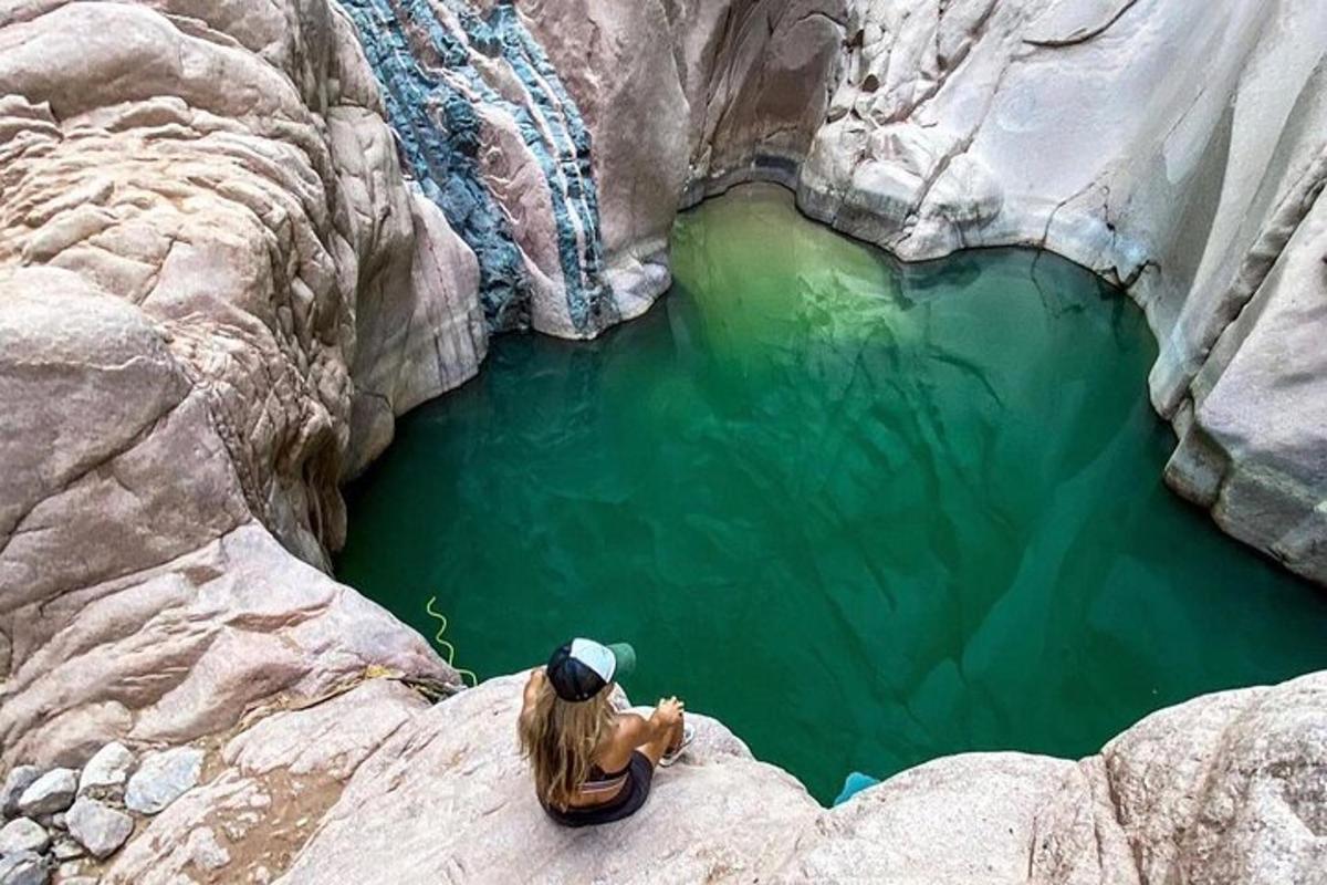 una dona asseguda en una roca a prop d'una massa d'aigua