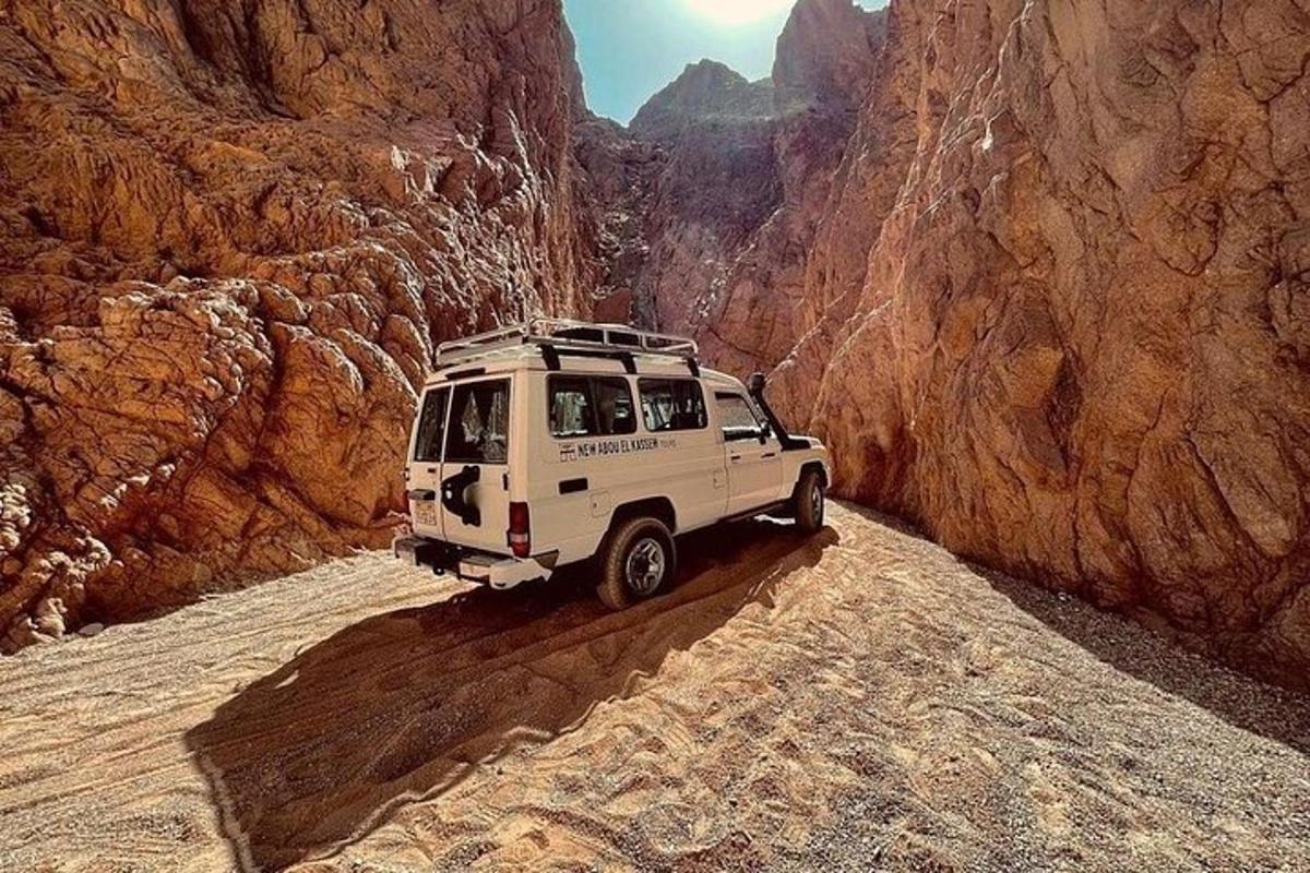 un jeep blanc conduint per un camí de terra en un canyó
