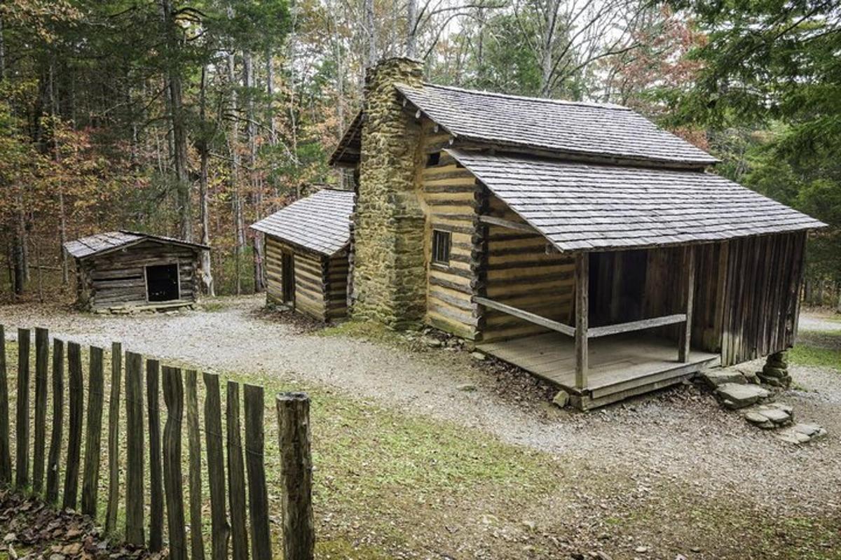 a wooden cabin in the woods next to a fence
