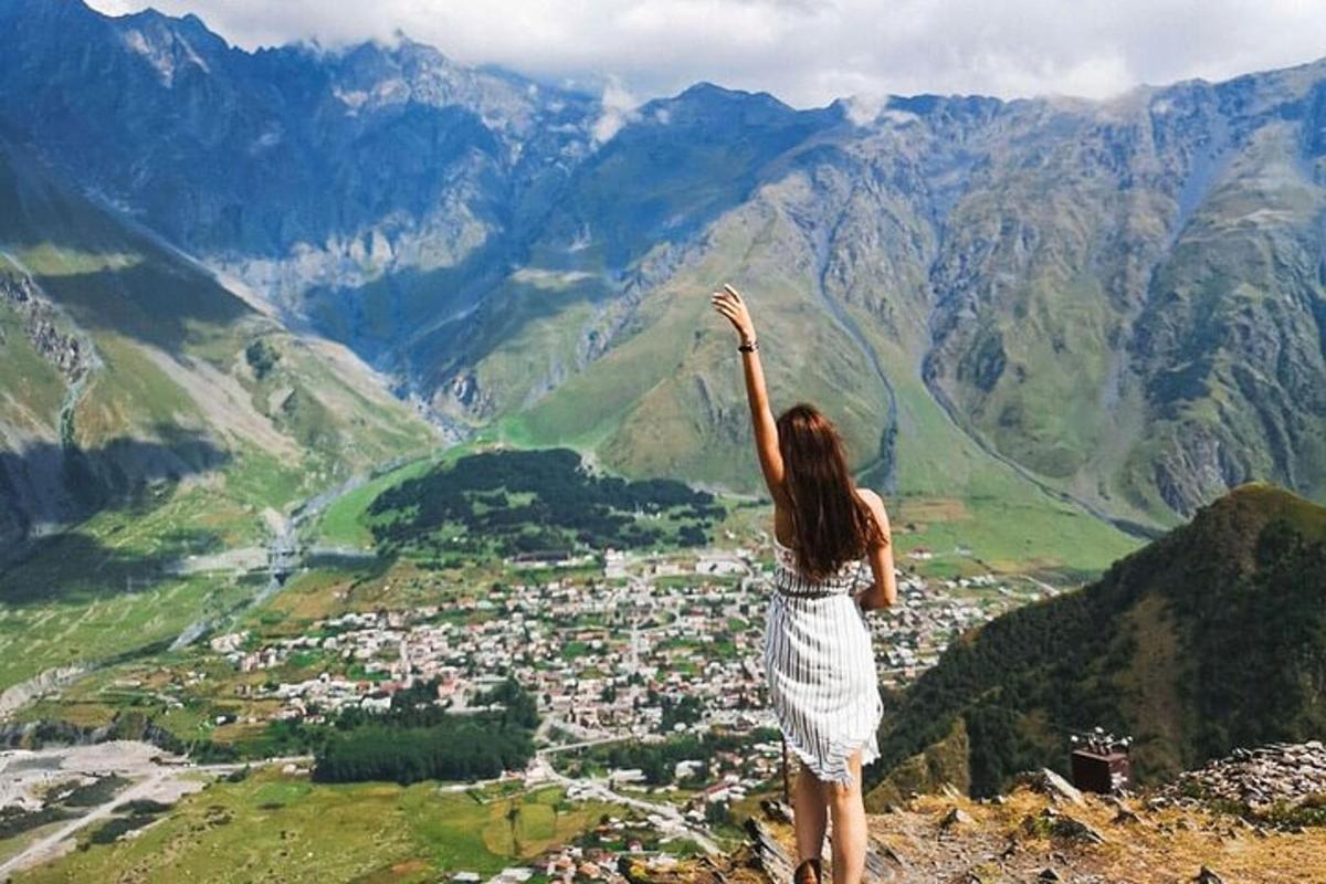 Una mujer parada en la cima de una montaña con la mano en el aire.