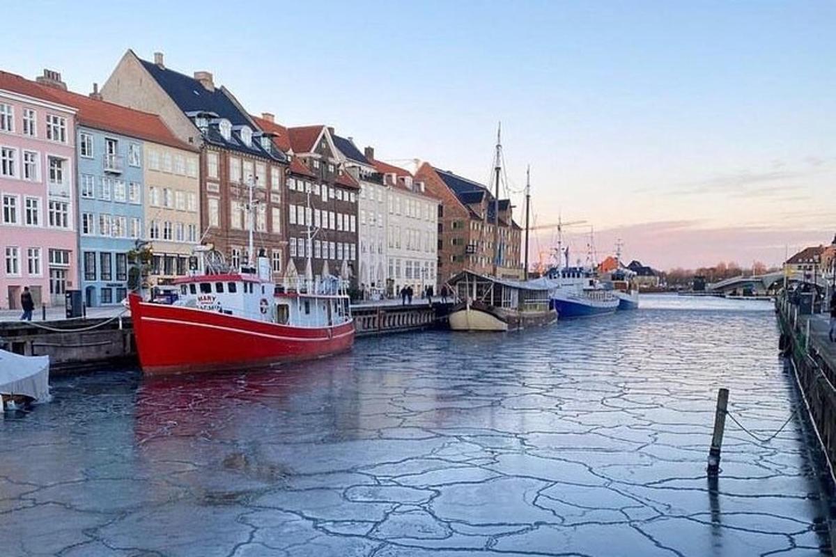 um barco vermelho e branco em um rio com edifícios