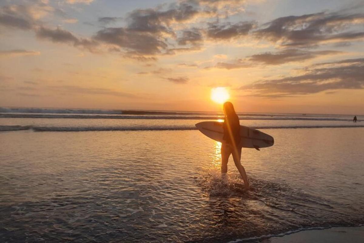seseorang berdiri di pantai dengan papan selancar