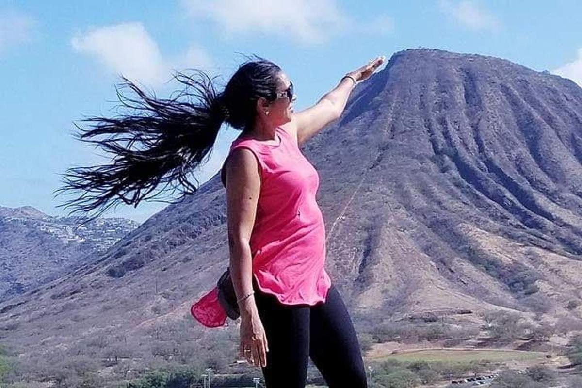 seorang wanita berambut panjang berdiri di hadapan sebuah gunung