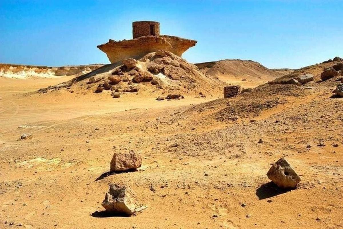 a desert with rocks and a building in the distance