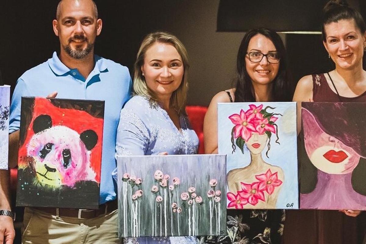 Un grupo de cuatro personas sosteniendo pinturas.