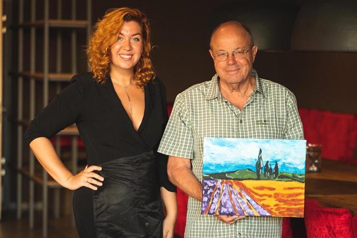 Una mujer parada junto a un hombre sosteniendo una pintura