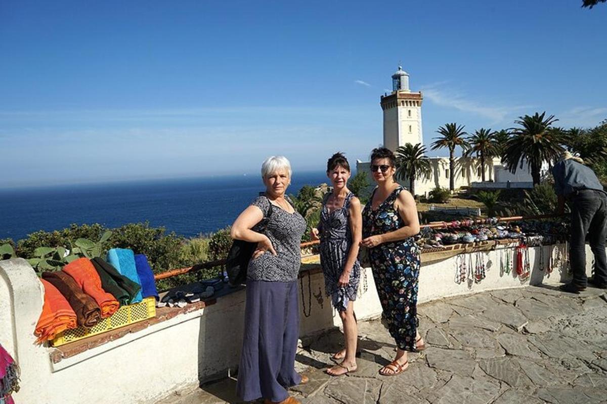 tre donne in piedi accanto a un muro con un faro