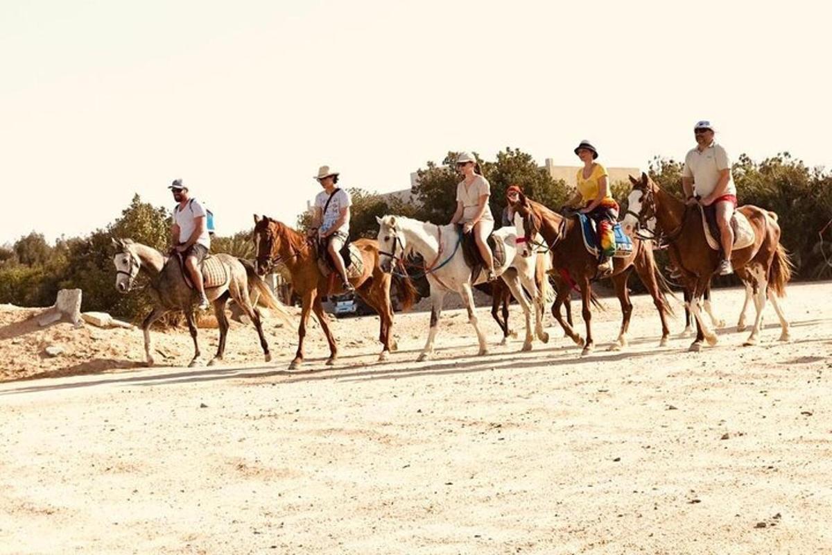 un grupo de personas montando a caballo en la playa
