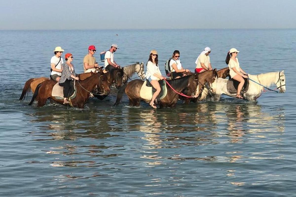 Un grupo de personas montando a caballo en el agua.