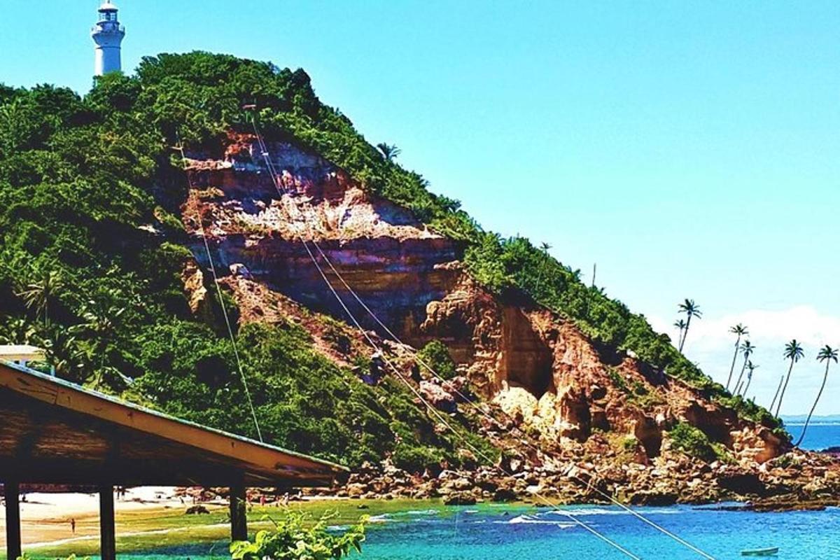 a lighthouse on top of a hill next to the ocean