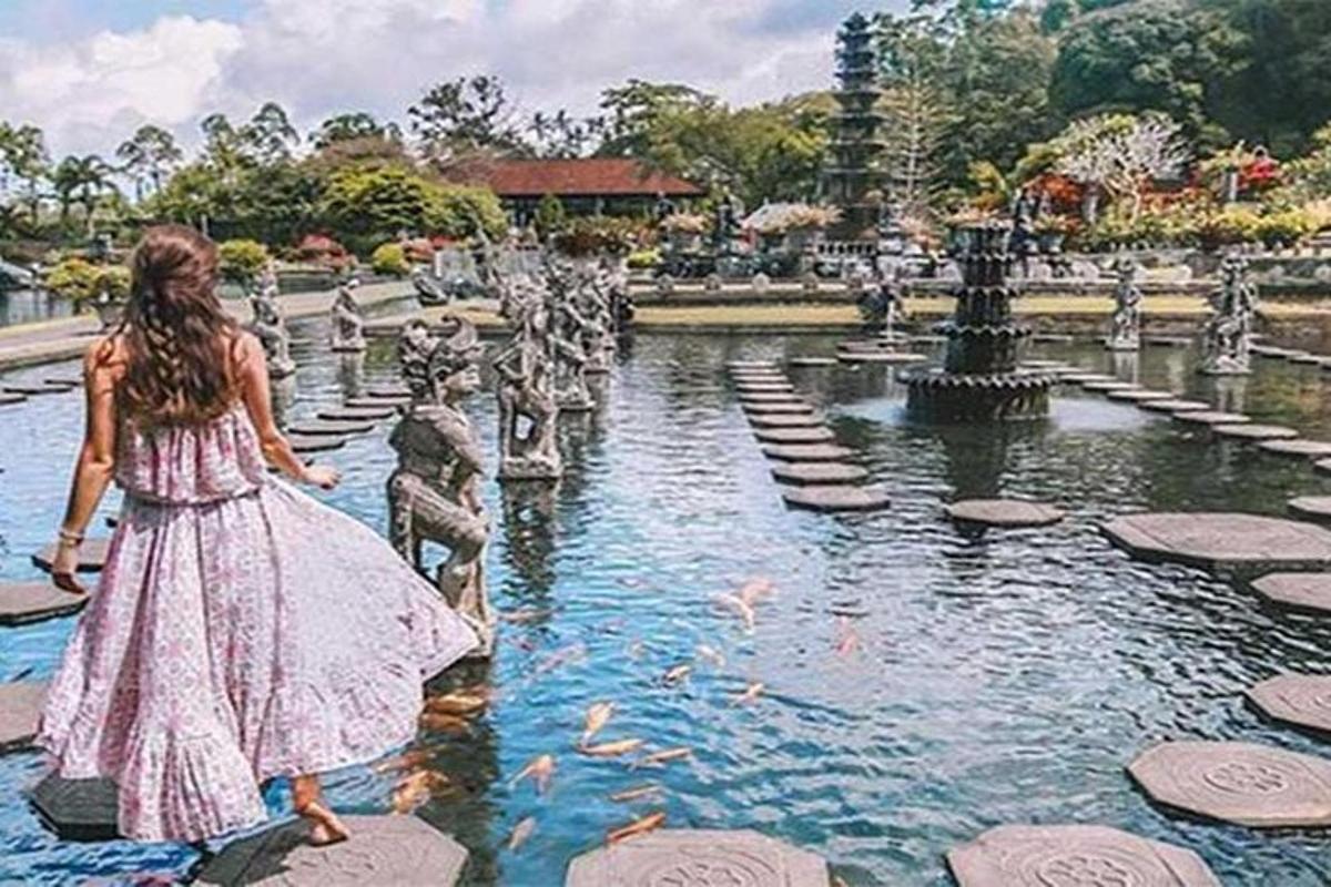 Una niña con un vestido caminando frente a una fuente.