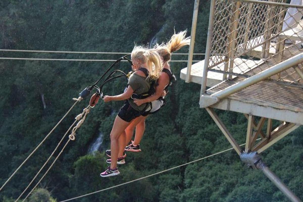two girls are zip lining on a zip line