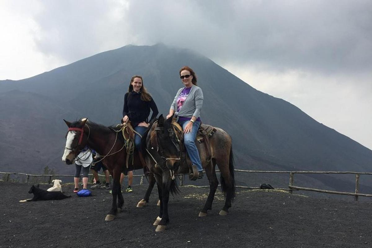 two women riding horses in front of a mountain