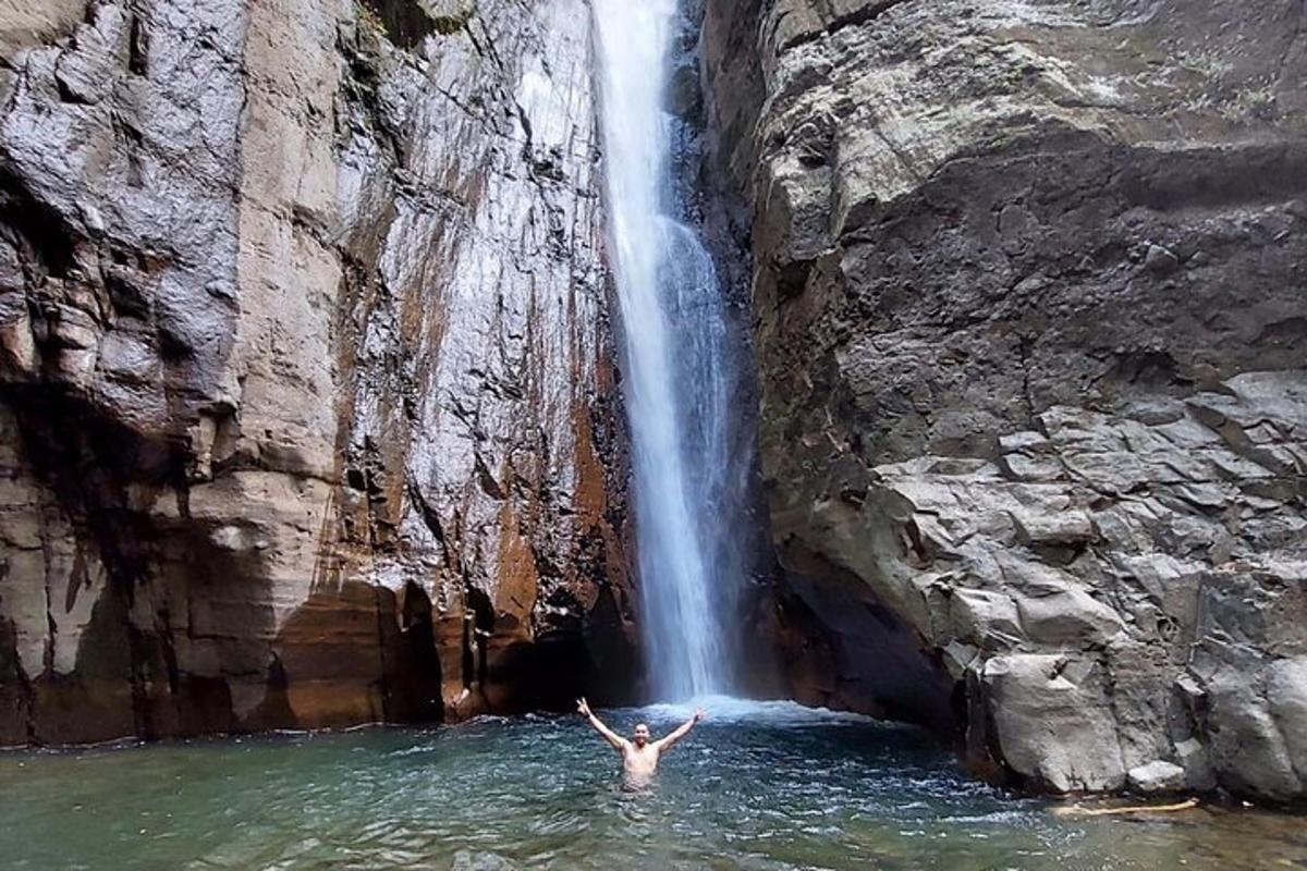 a person in the water in front of a waterfall