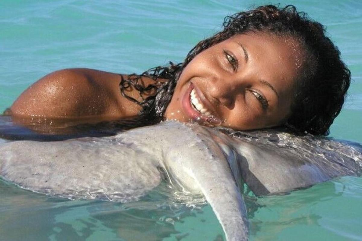 a woman laying in the water with a dolphin