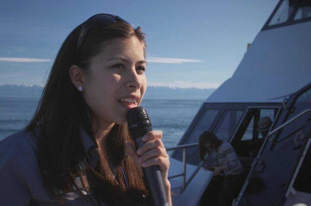 a woman holding a microphone in front of a boat