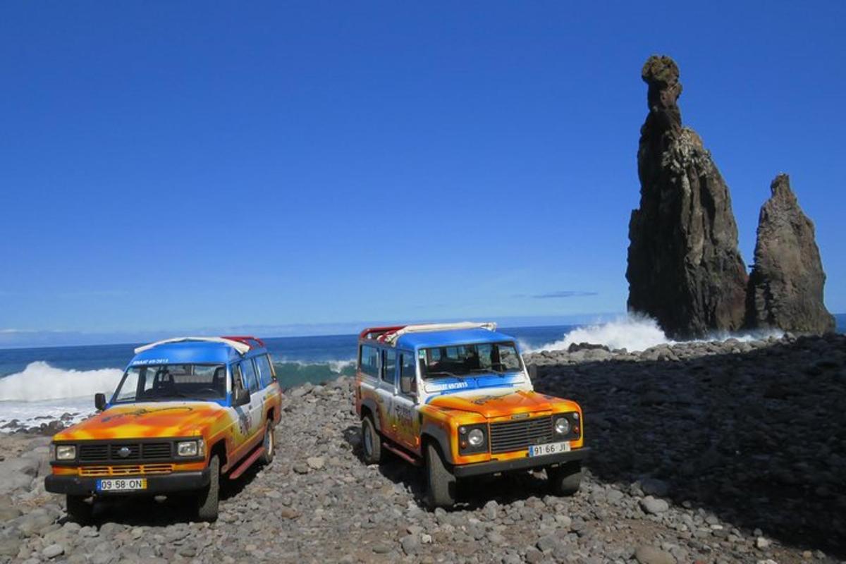 dois caminhões estacionados em uma praia rochosa perto do oceano
