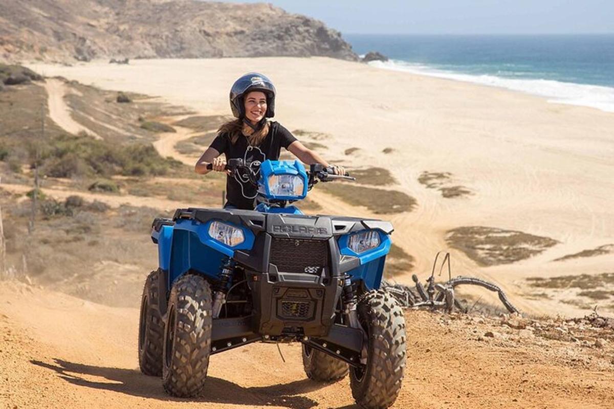 um homem pilotando um quadriciclo na praia