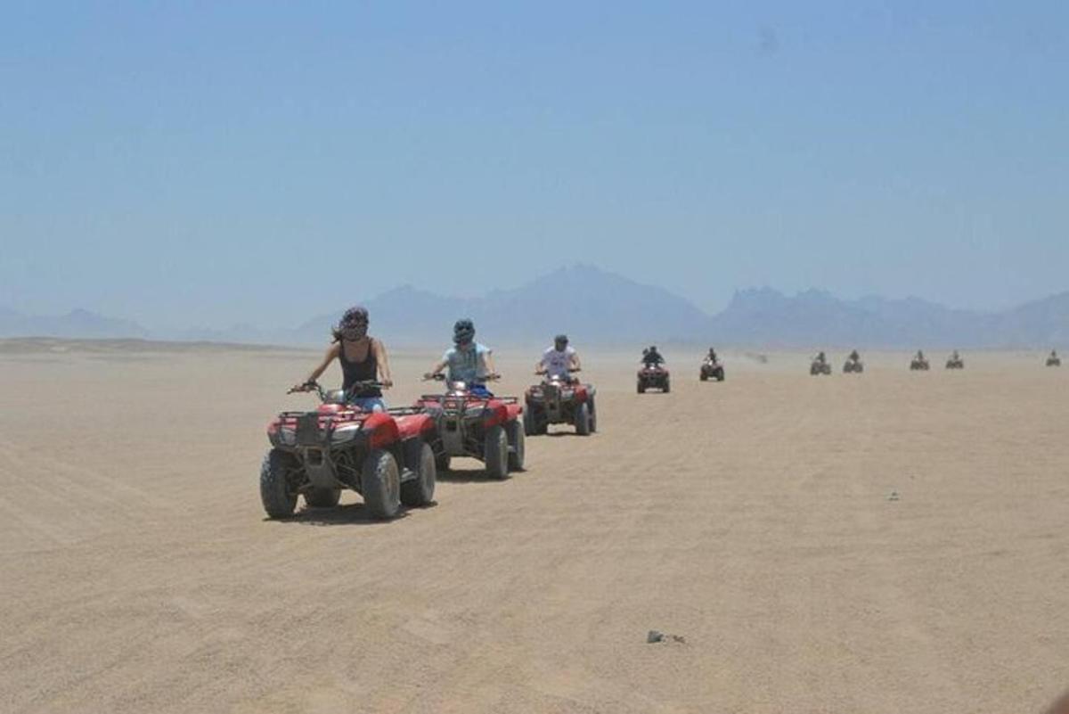 un grup de persones conduint quads al desert